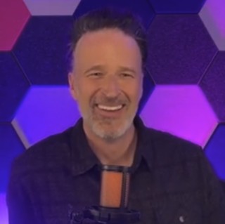 Drew Hopkins smiling at his podcast microphone